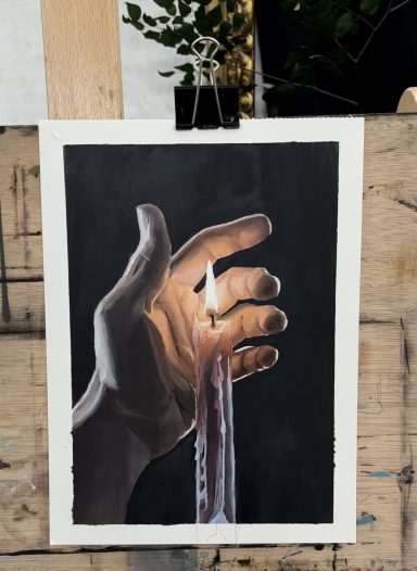 Mano sosteniendo una vela encendida con cera goteando, fondo oscuro.