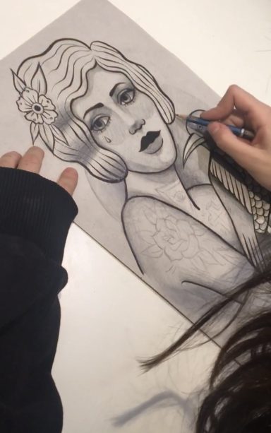 Dibujo en blanco y negro de mujer con cabello ondulado y flor, mano trabajando en el retrato.