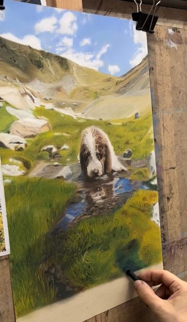 Un perro bebiendo agua de un arroyo en un paisaje montañoso con vegetación.